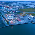 An aerial view of a petrochemical facility by water at twilight.