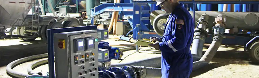 TETRA employee in blue overalls observing a frac water blending system.