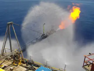 Plataforma marítima con el sistema de quema de gases y el sistema de rociado de agua activados.