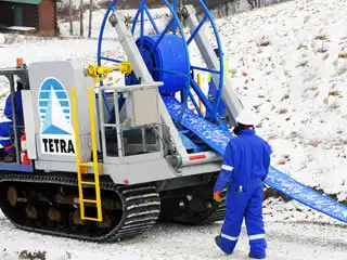 Un trabajador de TETRA se acerca a una unidad de transferencia de agua con manguera plana.