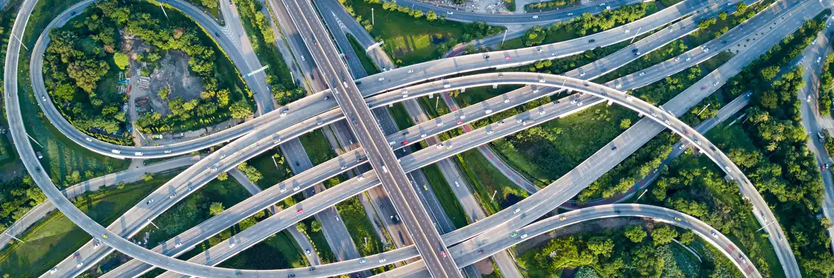 Flygfoto över en komplex motorvägskorsning med flera körfält och grönskande omgivningar på marknivå.