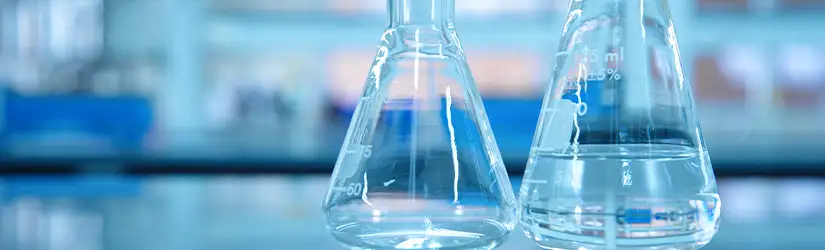 Dos matraces de vidrio de laboratorio, uno de ellos lleno hasta un cuarto de su capacidad con un líquido transparente.